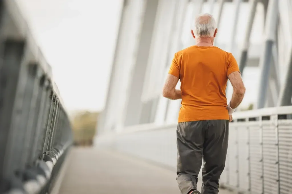Älterer Mann joggt über eine Brücke